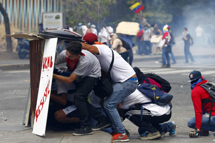 Anti-government protesters take cover behind makeshift shields during clashes with riot police in Caracas March 20, 2014. (Reuters)