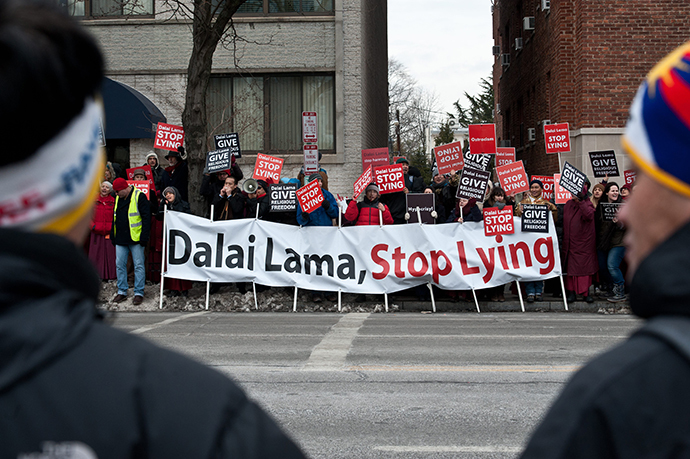 Supporters of Tibetan spiritual leader the Dalai Lama (front) watch members of the International Shugden Community protesting the Dalai Lama's "forcibly banning the religious practice of the Buddha Dorje Shugden and openly discriminating against people of this religious faith" outside the National Cathedral in Washington,DC on March 7, 2014. (AFP Photo / Nickolas Kamm)