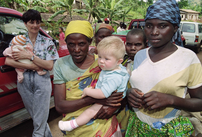 A Rwandan woman carries a Swiss family's baby 09 April 1994 at Butare on the Rwanda-Burundi border where numerous foreigners were fleeing the civil clashes in Rwanda. (AFP Photo / Pascal Guyot) 