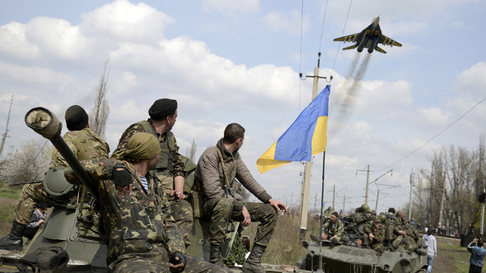 Ukrainian servicemen look at a Ukrainian military jet fly above them while they sit on top of armored personnel carriers in Kramatorsk April 16, 2014. (Reuters/Maks Levin)