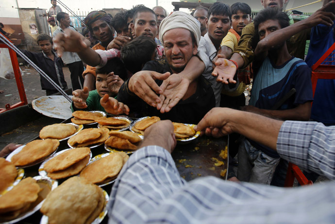 People reach out their hands as they wait to receive food provided by a charitable organisation outside a temple in New Delhi (Reuters)