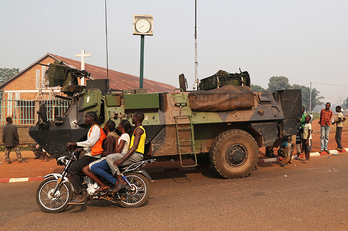 People ride on a motorcycle as they pass past a military vehicle in Wouango district January 9, 2014 (Reuters / Emmanuel Braun)