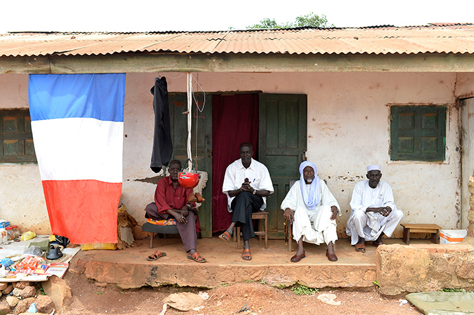 People sit next to a French flag in the village of Boda on April 7, 2014 (AFP Photo / Miguel Medina)