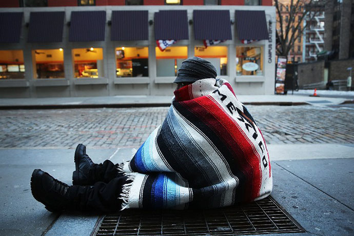 Prince, who is homeless, sits on a subway grate to keep warm on a frigid day on January 7, 2014 in New York, United States. (AFP Photo / Getty Images / Spencer Platt)