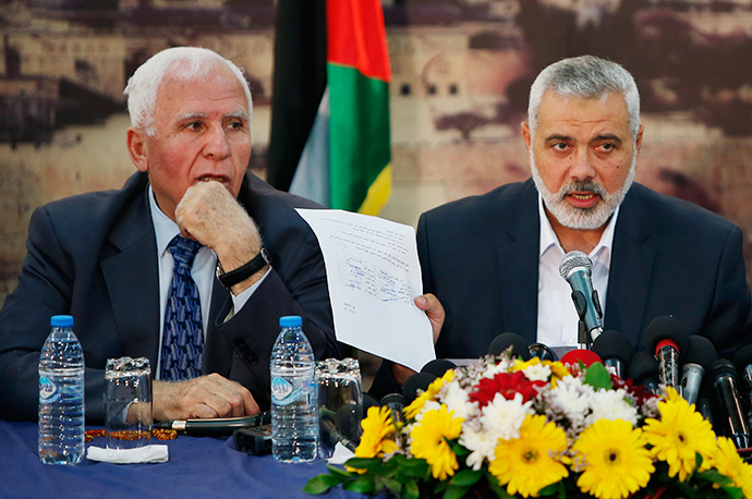 Head of the Hamas government Ismail Haniyeh shows a signed reconciliation agreement as he attends a news conference with Senior Fatah official Azzam Al-Ahmed (L) in Gaza City April 23, 2014 (Reuters / Suhaib Salem)
