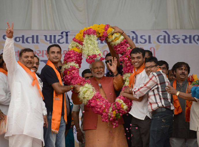 Chief Minister of the western Indian state of Gujarat and Bharatiya Janata Party (BJP) Prime Ministeral candidate Narendra Modi (C) gestures as he is offered a garland of flowers by supporters during an election rally in Vallabh Vidyanagar, some 85 kms from Ahmedabad on April 28, 2014. (AFP Photo / Sam Panthaky)