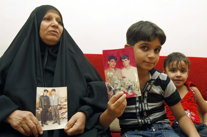 The mother and son of Baha Mousa (R in the picture), an Iraqi hotel receptionist who was kicked and beaten to death whilst in British Army custody, hold pictures of him at their house in Basra, 420 km (260 miles) southeast of Baghdad September 7, 2011.(Reuters/Atef Hassan)