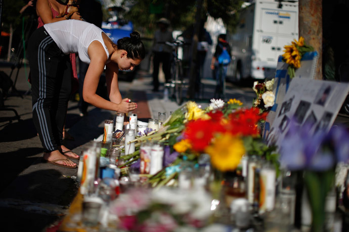 A woman lights a candle at a makeshift memorial for 20-year-old UCSB student Christopher Michael-Martinez outside a deli that was one of nine crime scenes after series of drive-by shootings that left 7 people dead in the Isla Vista neighborhood of Santa Barbara, California May 25, 2014. (Reuters / Lucy Nicholson)