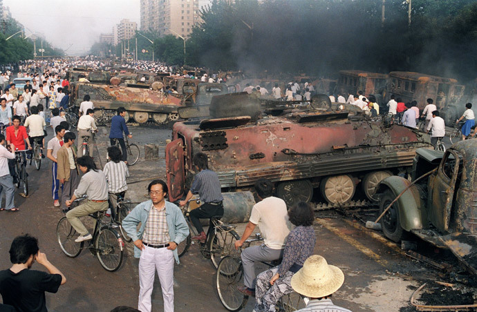 (FILES) In a ilfe picture taken on June 4, 1989 Beijing residents gather around the smoking remains of over 20 armoured personnel carriers burnt by demonstrators during clashes with soldiers near Tiananmen Square. (AFP Photo / Files / Manuel Ceneta)