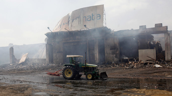 A tractor runs past a damaged building on the tarmac of Jinnah International Airport, after Sunday's attack by Taliban militants, in Karachi June 10, 2014.(Reuters / Athar Hussain )