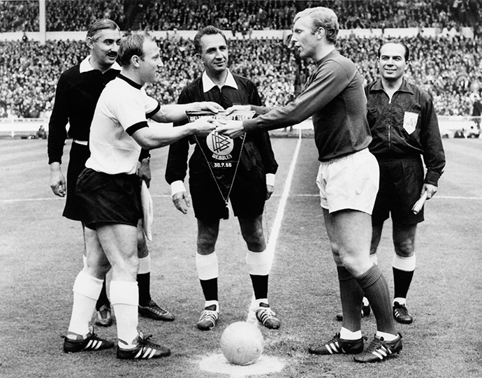 West Germany's and England's national soccer team captains, Uwe Seeler (L) and Bobby Moore, exchange pennants as Swiss referee Gottfried Dienst (C) looks on before the start of the World Cup final on 30 July 1966 at Wembley stadium in London (AFP Photo)