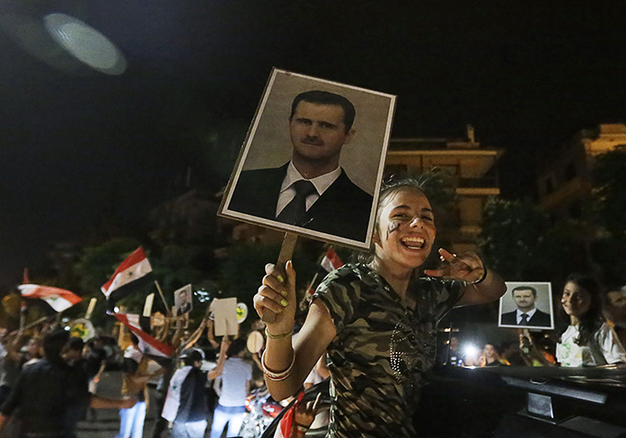A girls gestures and holds a picture of re-elected Syrian President Bashar al-Assad as she celebrates in Damascus after Assad was announced as the winner of the country's presidential elections on June 4, 2014 (AFP Photo)