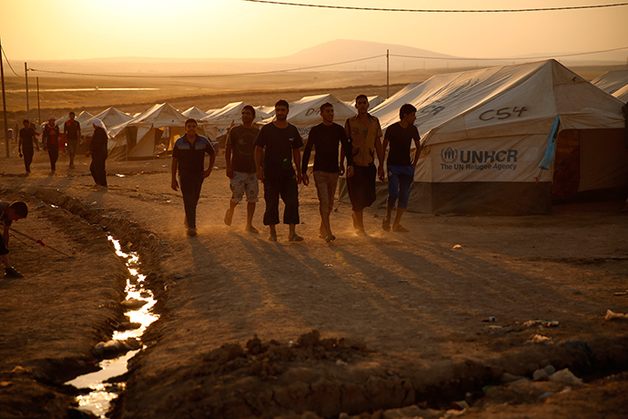Iraqi refugees, who fled from the violence in Mosul, walk during sunset inside the Khazer refugee camp on the outskirts of Arbil, in Iraq's Kurdistan region, June 27, 2014 (Reuters / Ahmed Jadallah)