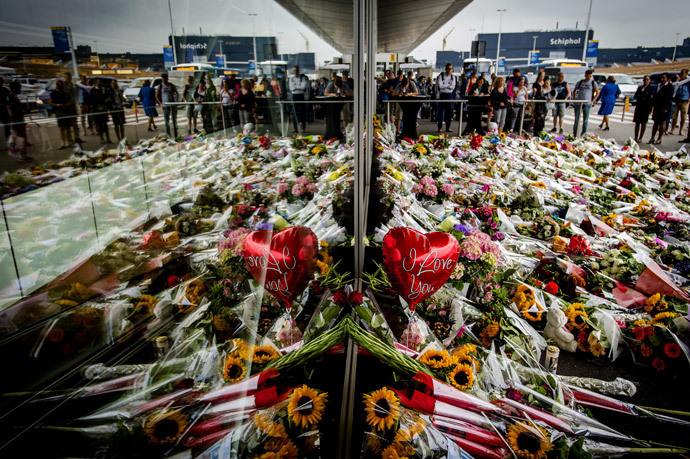 People look at the flowers left in remembrance for the victims of the MH17 plane crash at Schiphol Airport, near Amsterdam, on July 21, 2014 (AFP Photo / ANP / Robyn Van Lonkhuijsen Netherlands out)