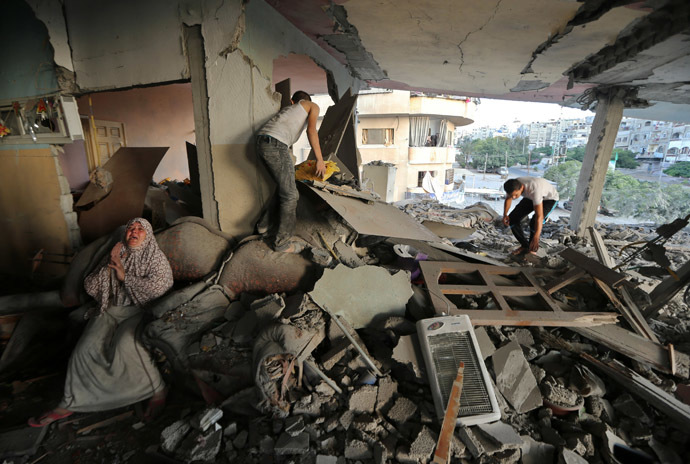 A Palestinian woman (L) cries inside her damaged house, which police said was targeted in an Israeli air strike, in Gaza City July 17, 2014. (Reuters/Mohammed Salem)