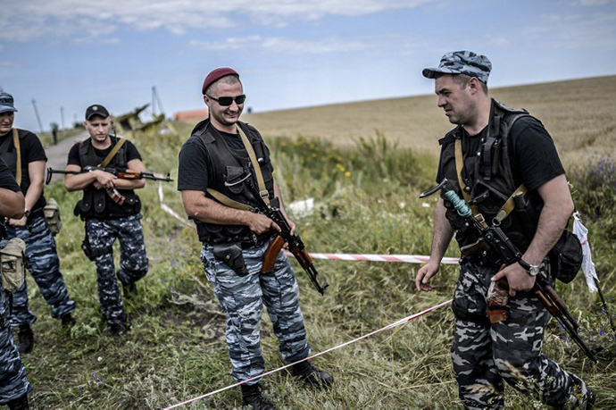 Armed members of self-defense forces stand guard in front of the crash site of Malaysia Airlines Flight MH17, near the village of Grabove, in the region of Donetsk on July 20, 2014. (AFP Photo / Bulent Kilic)