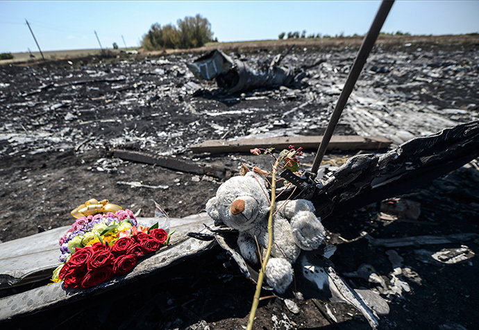 Flowers and a teddy bear, left by parents of an Australian victim of the crash, laid on a piece of the Malaysia Airlines plane MH17, near the village of Hrabove (Grabove), in the Donetsk region. (AFP Photo / Bulent Kilic)