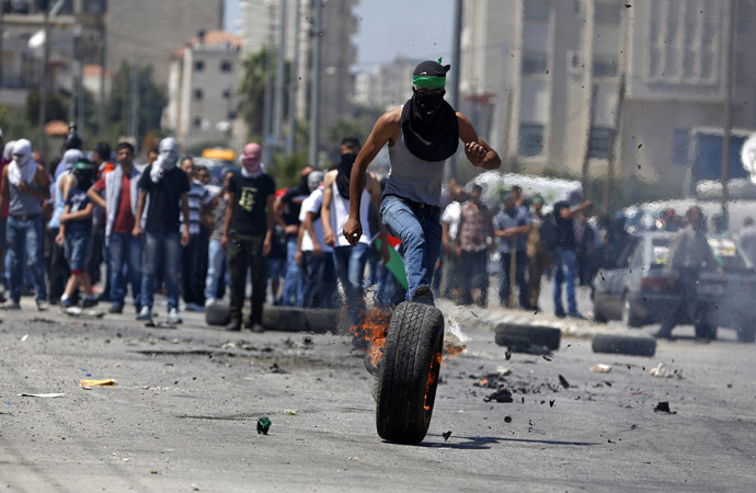 A Palestinian protester kicks a burning tyre during clashes with Israeli troops at a protest against the Israeli offensive in Gaza, outside Israel's Ofer military prison near the West Bank city of Ramallah August 1, 2014 (Reuters)