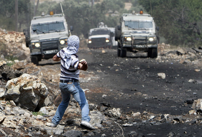 A Palestinian protester throws stones toward Israeli troops during clashes following a protest against the nearby Jewish settlement of Qadomem, in the West Bank village of Kofr Qadom near Nablus May 16, 2014. (Reuters)