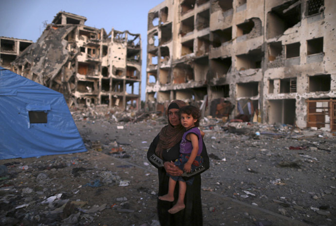 A Palestinian woman carries her daughter as she leaves her house near the remains of residential buildings in Beit Lahiya town, which witnesses said was heavily hit by Israeli shelling and air strikes during the Israeli offensive, in the northern Gaza Strip August 7, 2014. (Reuters)