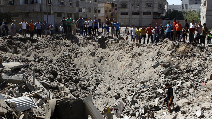 People look at a crater on the ground and damaged buildings, that witnesses said was caused by an Israeli air strike, in the Zeitoun neighbourhood in Gaza City August 8, 2014. (Reuters)