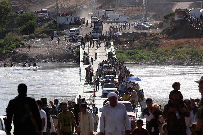 Displaced people from the minority Yazidi sect, fleeing the violence in the Iraqi town of Sinjar, re-enter Iraq from Syria at the Iraqi-Syrian border crossing in Fishkhabour, Dohuk province, August 10, 2014 (Reuters / Ari Jalal)