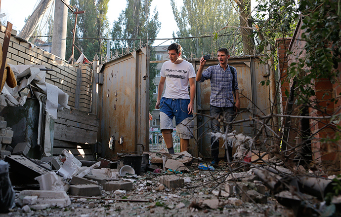 People walk in front of a building damaged by, what locals say, was recent shelling by Ukrainian forces in Donetsk August 20, 2014 (Reuters / Maxim Shemetov)