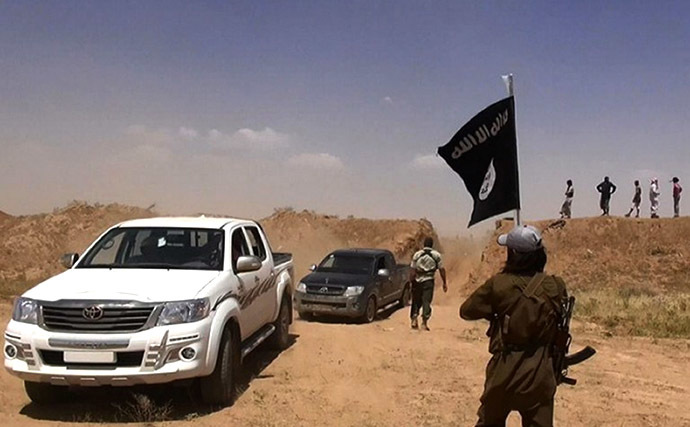 An image made available by the jihadist Twitter account Al-Baraka news on June 11, 2014 allegedly shows a militant of the jihadist group Islamic State of Iraq and the Levant (ISIL) waving the Islamic Jihad flag as vehicles drive on a newly cut road through the Syrian-Iraqi border between the Iraqi Nineveh province and the Syrian town of Al-Hasakah. (AFP Photo)