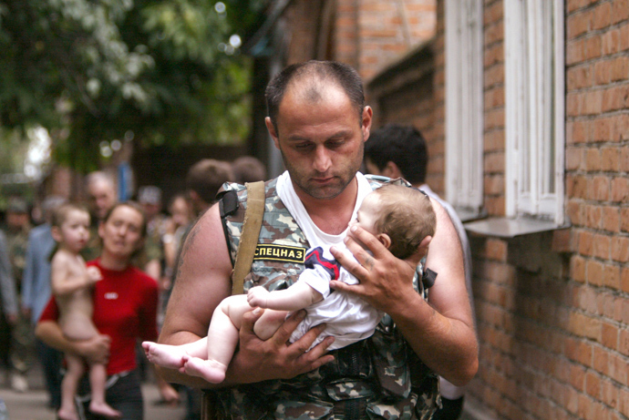 A Russian police officer carries a released baby from the school seized by heavily armed masked men and women in the town of Beslan (Reuters / Viktor Korotayev)