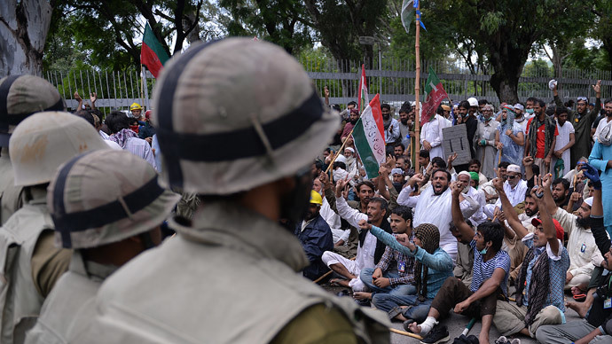 Pakistani soldiers stand guard as supporters of Canadian cleric Tahir ul Qadri and cricketer-turned politician Imran Khan shout anti-government slogans outside the prime minister's residence in Islamabad on September 1, 2014. (AFP Photo / Aamir Qureshi)