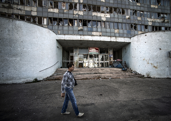 A Lugansk resident walks past a building damaged by artillery shelling. (RIA Novosti / Evgeny Biyatov)