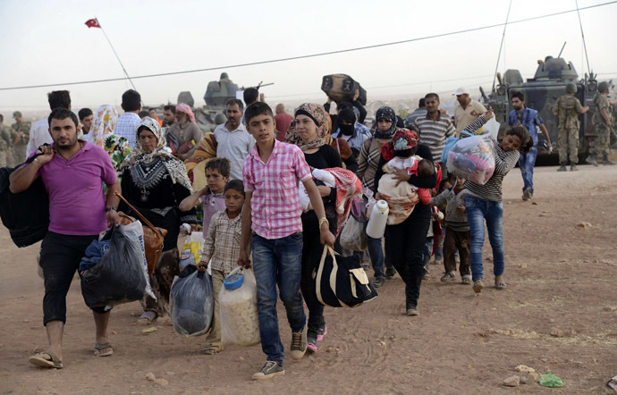 Syrian Kurds walk with their belongings after crossing into Turkey at the Turkish-Syrian border, near the southeastern town of Suruc in Sanliurfa province, September 20, 2014. (Reuters/Stringer)