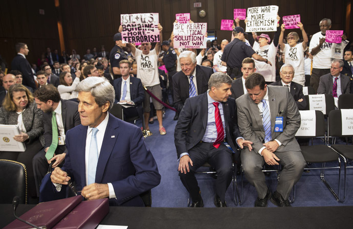 Anti-war protesters wave signs as U.S. Secretary of State John Kerry arrives to testify to a Senate Foreign Relations Committee hearing on "U.S. Strategy to Defeat the Islamic State in Iraq and the Levant" on Capitol Hill in Washington September 17, 2014. (Reuters/Joshua Roberts)