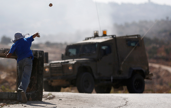 A Palestinian protester hurls a stone towards an Israeli army jeep during clashes at a protest against the Jewish settlement of Ofra, in the West Bank village of Silwad, near Ramallah September 19, 2014 (Reuters / Mohamad Torokman)