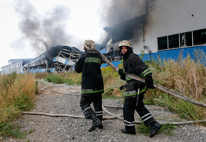Firefighters pull a hose as they work to extinguish a fire at a printing factory hit by what locals say, was recent shelling by Ukrainian forces in Donetsk August 23, 2014 (Reuters / Maxim Shemetov)