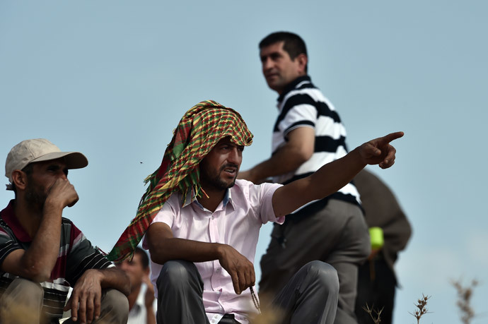 A Kurdish man gestures next to others as they watch fighting from a hill at the Turkish-Syrian border, in the southeastern Turkish village of Mursitpinar, Sanliurfa province, across from the Syrian town of Ain al-Arab, known as Kobane by the Kurds, on October 9, 2014. Turkish soldiers stand near a tank on a hill at the Turkish-Syrian border, in the southeastern Turkish village of Mursitpinar, Sanliurfa province, across from the Syrian town of Ain al-Arab, known as Kobane by the Kurds, on October 9, 2014. (AFP Photo / Aris Messinis)