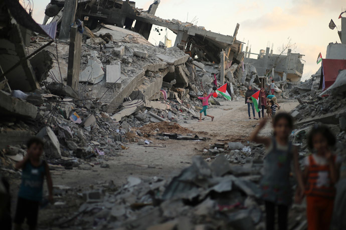 Palestinian children hold Palestinian flags as they play near the ruins of their houses, which witnesses said were destroyed during the seven-week Israeli offensive, in the devastated area of the east of Gaza City September 22, 2014. (Reuters/Mohammed Salem)