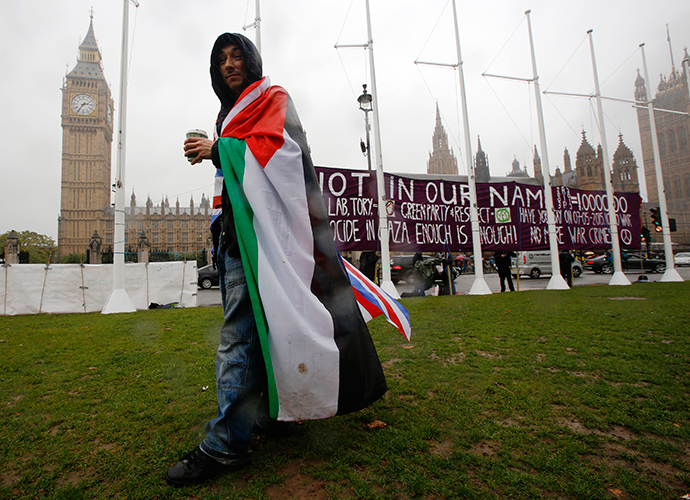 A pro-Palestine supporter wears a Palestinian and Union flag outside the Houses of Parliament in London October 13, 2014. (Reuters / Luke MacGregor)