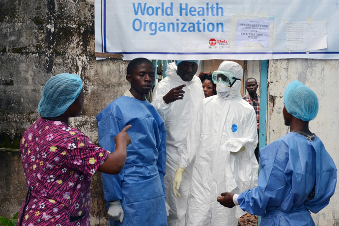 Health workers in protective gear pose at the entrance of the Ebola treatment unit of the John F. Kennedy Medical Center, in the Liberian capital Monrovia, on October 13, 2014. (AFP Photo / Zoom Dosso)