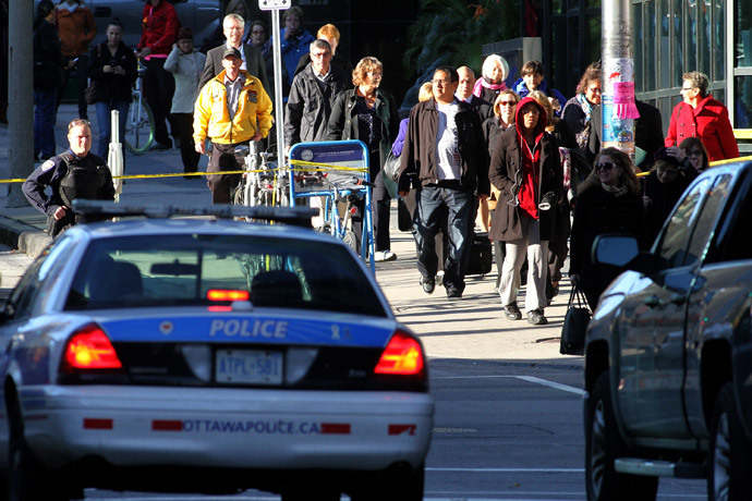 Police officers watch as commuters who spent the day in lockdown, head home in Ottawa, Canada on October 22, 2014.(AFP Photo / Lars Hagberg)