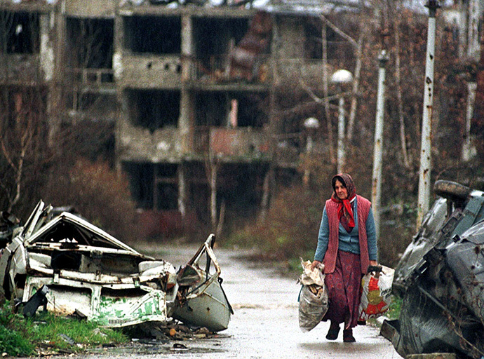 An elderly woman carries her belongings November 22 in Sarajevo's war shattered airport settlement. (Reuters)