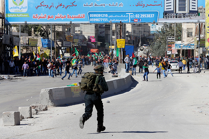 An Israeli border policeman runs during clashes with Palestinian stone throwers following a protest against what organizers say are recent visits by Jewish activists to al-Aqsa mosque, at Qalandia checkpoint near the West Bank city of Ramallah November 7, 2014 (Reuters / Ammar Awad)