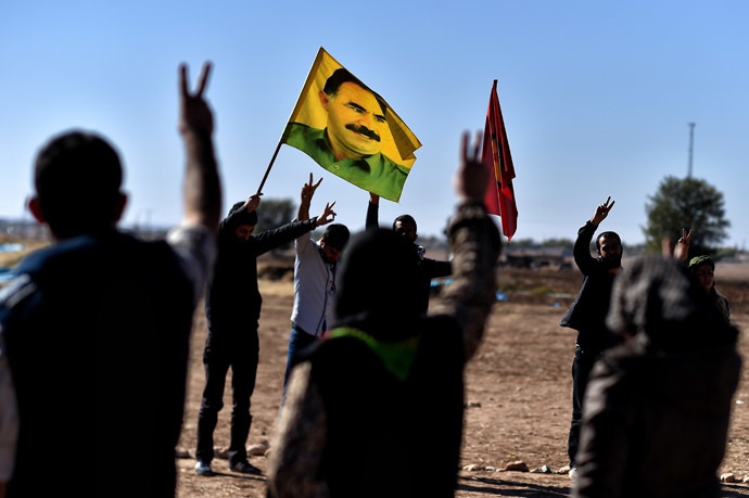 A man holds a flag with a portrait of the detained Kurdistan Workers Party (PKK) rebel leader Abdullah Ocalan, during a Kurdish people demonstration, in the southeastern border village of Mursitpinar, Sanliurfa province, on November 9, 2014. (AFP Photo/Aris Messinis)