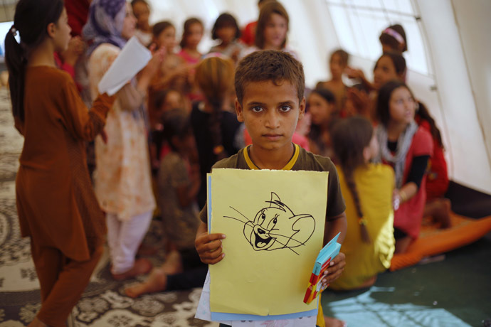 A displaced Iraqi child, who fled from the violence in Mosul by the Islamic State (IS), displays his drawing during refresher courses at the start of a school year organized by UNICEF at Baherka refugee camp in Erbil September 11, 2014. (Reuters/Ahmed Jadallah)