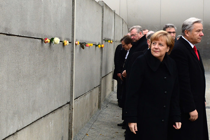 German Chancellor Angela Merkel (2ndR) and Berlin Mayor Klaus Wowereit (R) leave after putting roses in a preserved segment of the Berlin Wall during the commemorations to mark the 25th anniversary of the fall of the Berlin Wall at the Berlin Wall Memorial in the Bernauer Strasse in Berlin, on November 9, 2014. (AFP Photo / John Macdougall)