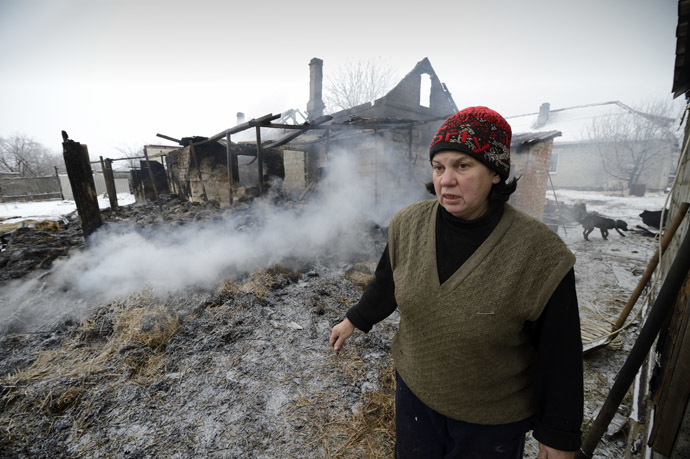 A woman stands by her smoldering home in the Lidievka district, after it was hit and destroyed by shelling in the eastern Ukrainian city of Donetsk on December 6, 2014. (AFP Photo/Eric Feferberg)