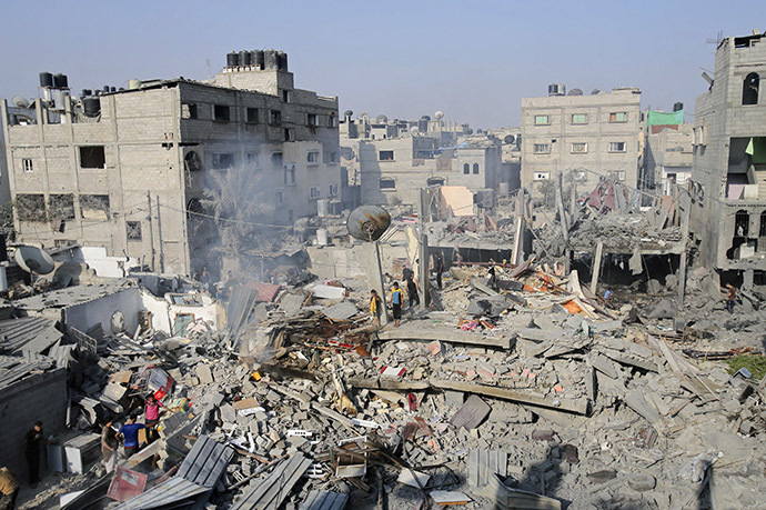 Palestinians stand on what witnesses say was a house destroyed by an Israeli air strike in Rafah, southern Gaza. (Reuters/Ibraheem Abu Mustafa)