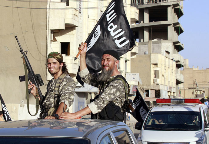 Militant Islamist fighters wave flags as they take part in a military parade along the streets of Syria's northern Raqqa province June 30, 2014. (Reuters)