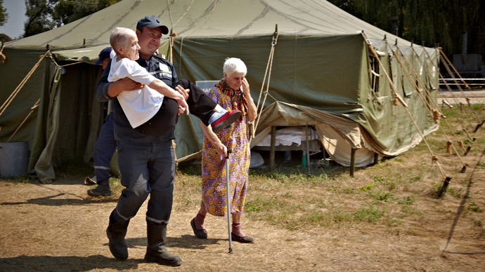 An employee of the Ukrainian Emergencies Ministry carries an old woman who came from the anti-terrorist operation area to a transit point for displaced persons in the city of Svatovo in the Lugansk Region.(RIA Novosti / Sergey Kozlov)