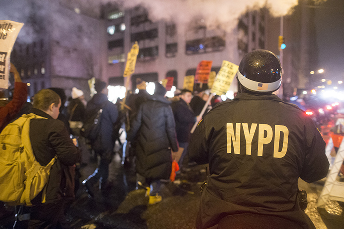 An NYPD Officer on a motorbike keeps track of anti-NYPD protesters as they march through the Upper East Side of Manhattan on December 23, 2014 in New York City (AFP Photo / Michael Graae)